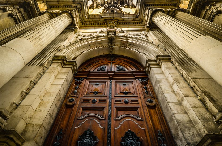Close-up view of a grand gothic cathedral entrance with detailed columns and a historic wooden door.